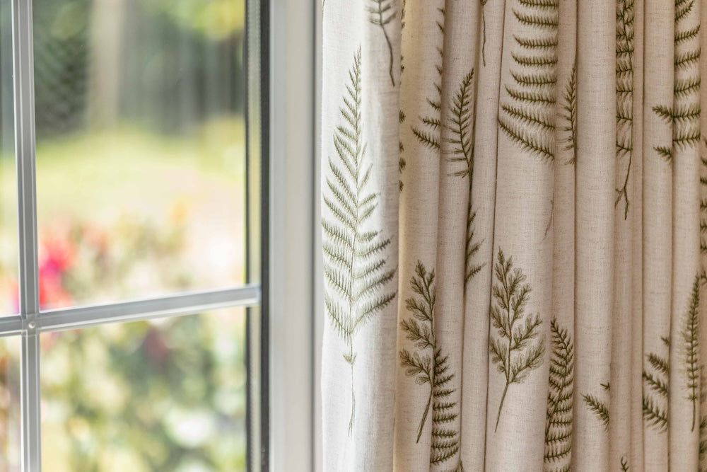 Curtain with leaf pattern in front of a window with a view of greenery