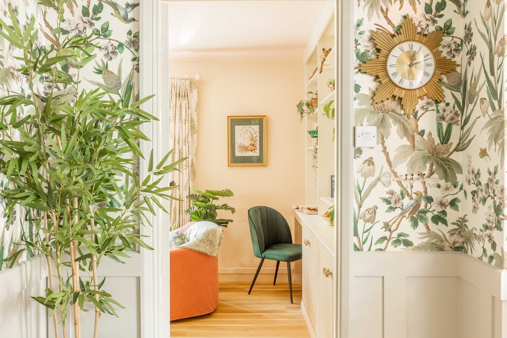 Decorative interior with floral wallpaper, green chair, and clock.