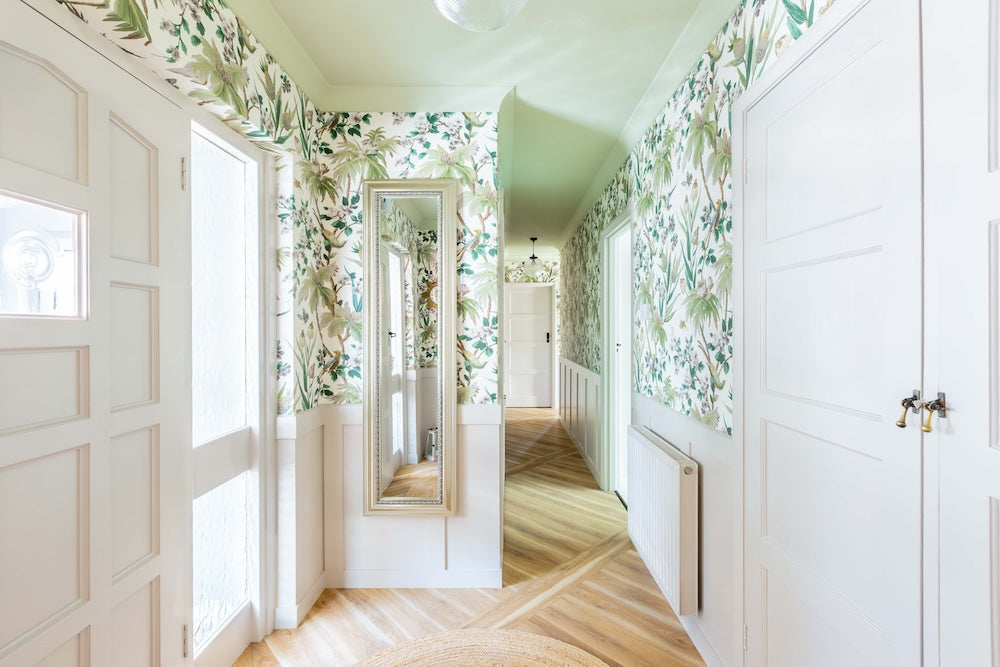 Hallway with floral wallpaper, green ceiling, wooden floor, and a mirror.