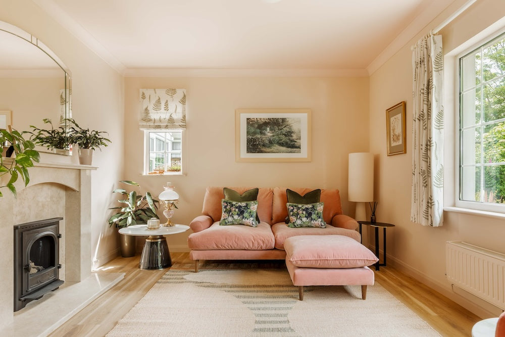 Living room with pink sofa and walls, fireplace, and large window