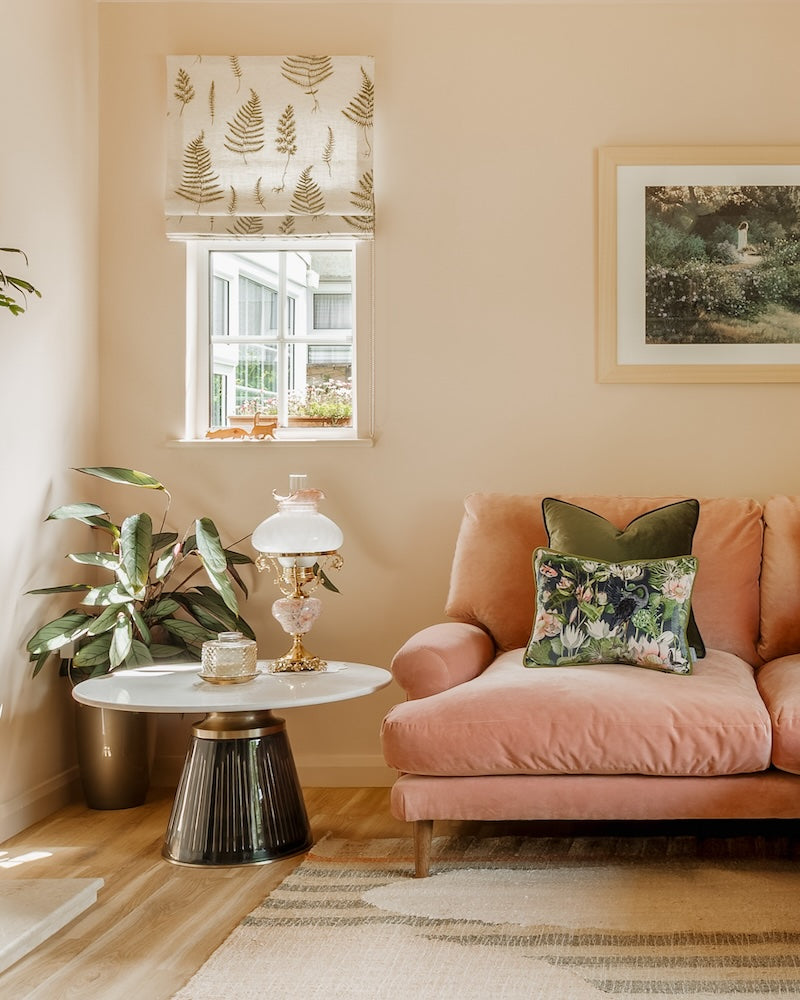 Living room with pink sofa, decorative pillows, and a small table with a glass lamp.