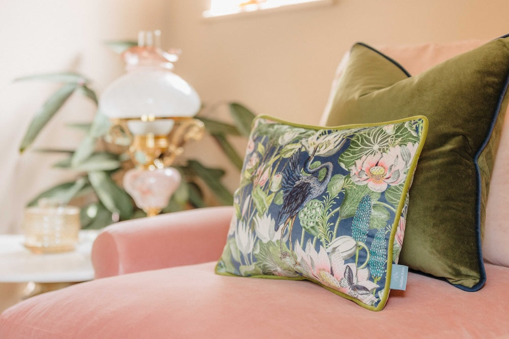 Tropical patterned pillow on a pink sofa with pink walls.