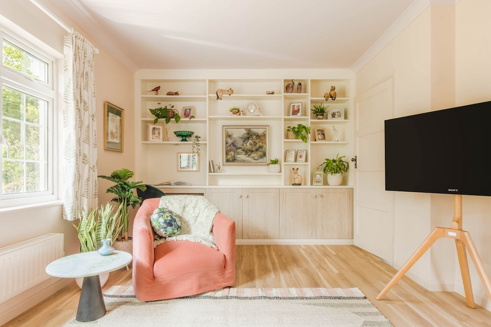 Modern living room with a pink armchair, TV, and bookshelf.